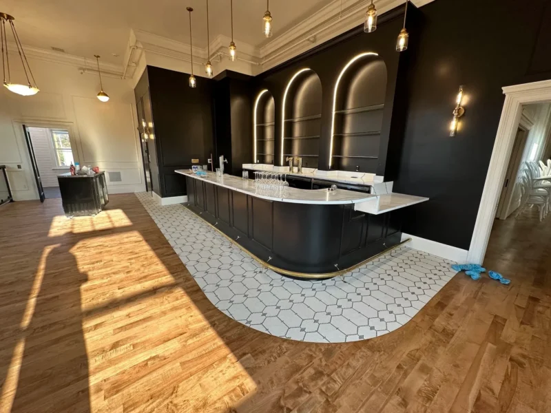 Black arched bar shelving with illuminated alcoves and white hex tile flooring