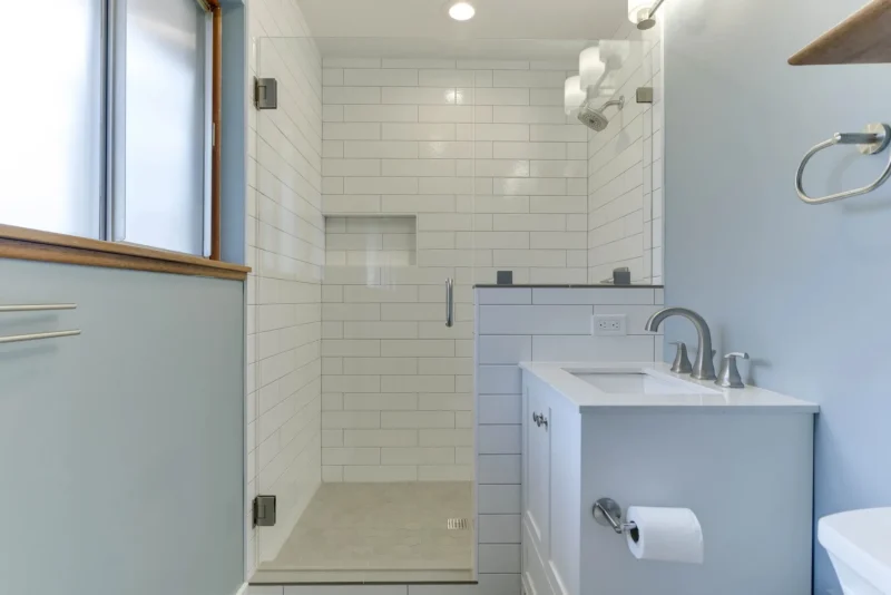 Compact white bathroom with subway tile shower, glass partition, and modern vanity sink