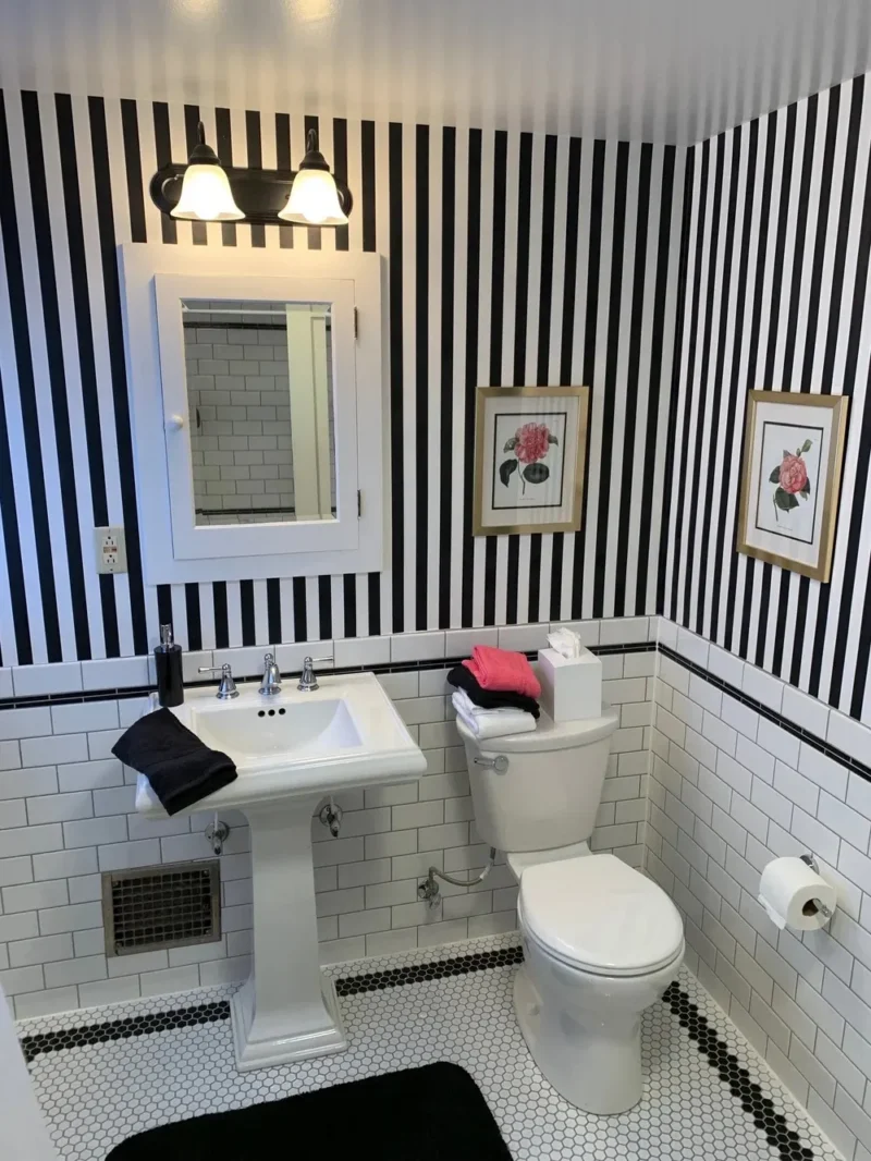 Black-and-white striped bathroom with pedestal sink, subway tile walls, and hexagon mosaic floor