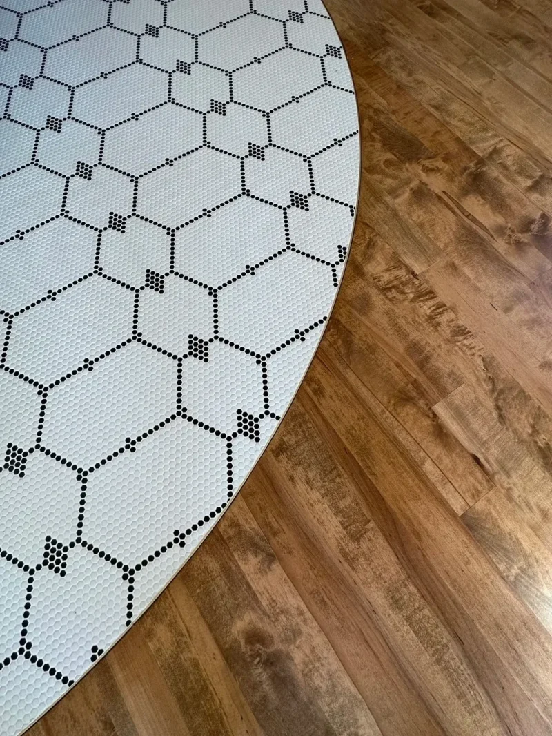 Curved mosaic tile border beside warm wood flooring