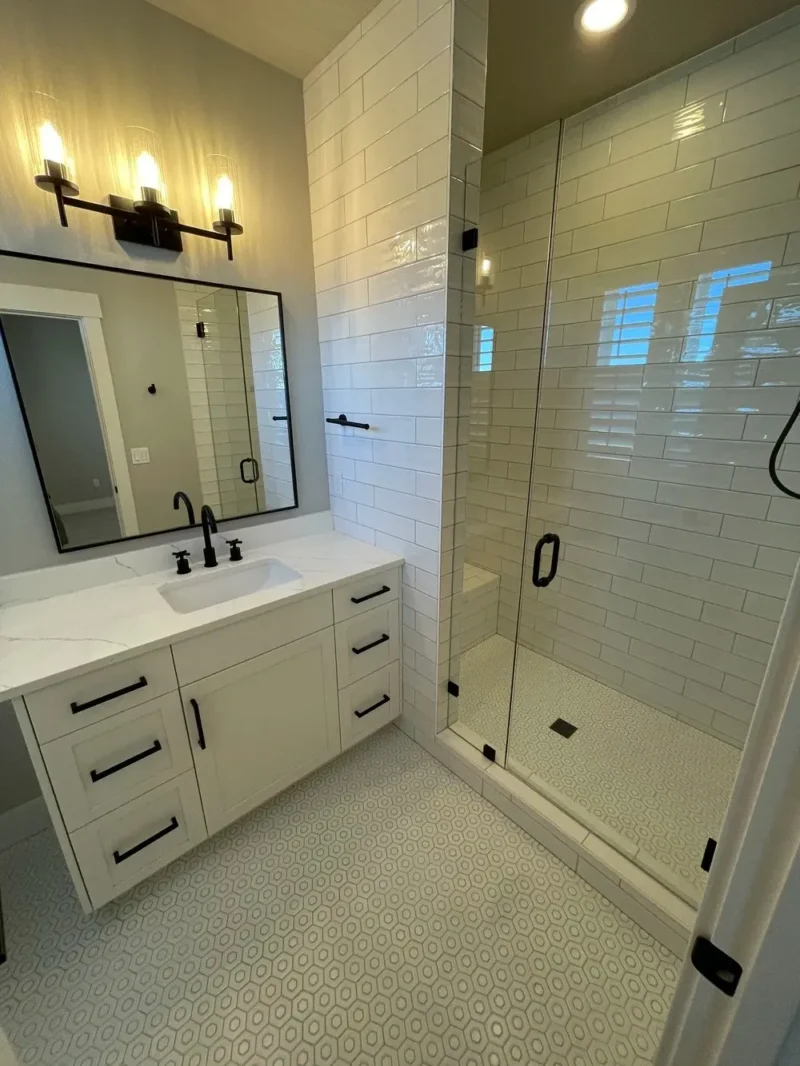 Modern white bathroom with subway tile shower, hexagon flooring, and black fixtures