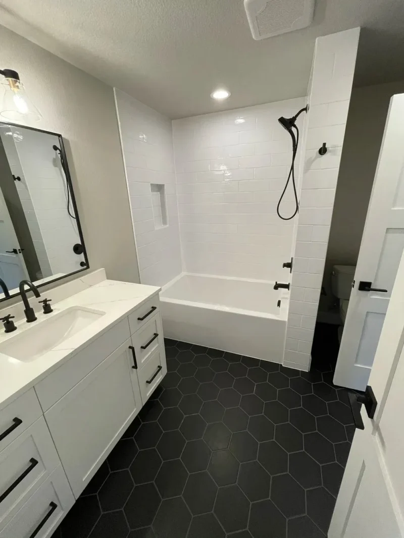 Modern white bathroom with black hexagon flooring and subway tile bathtub surround