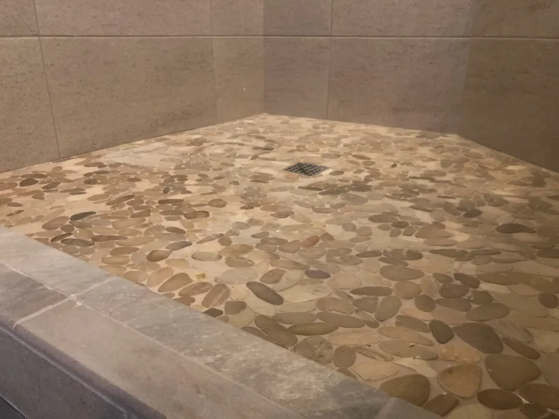 Pebble shower floor with square drain and gray tiled walls