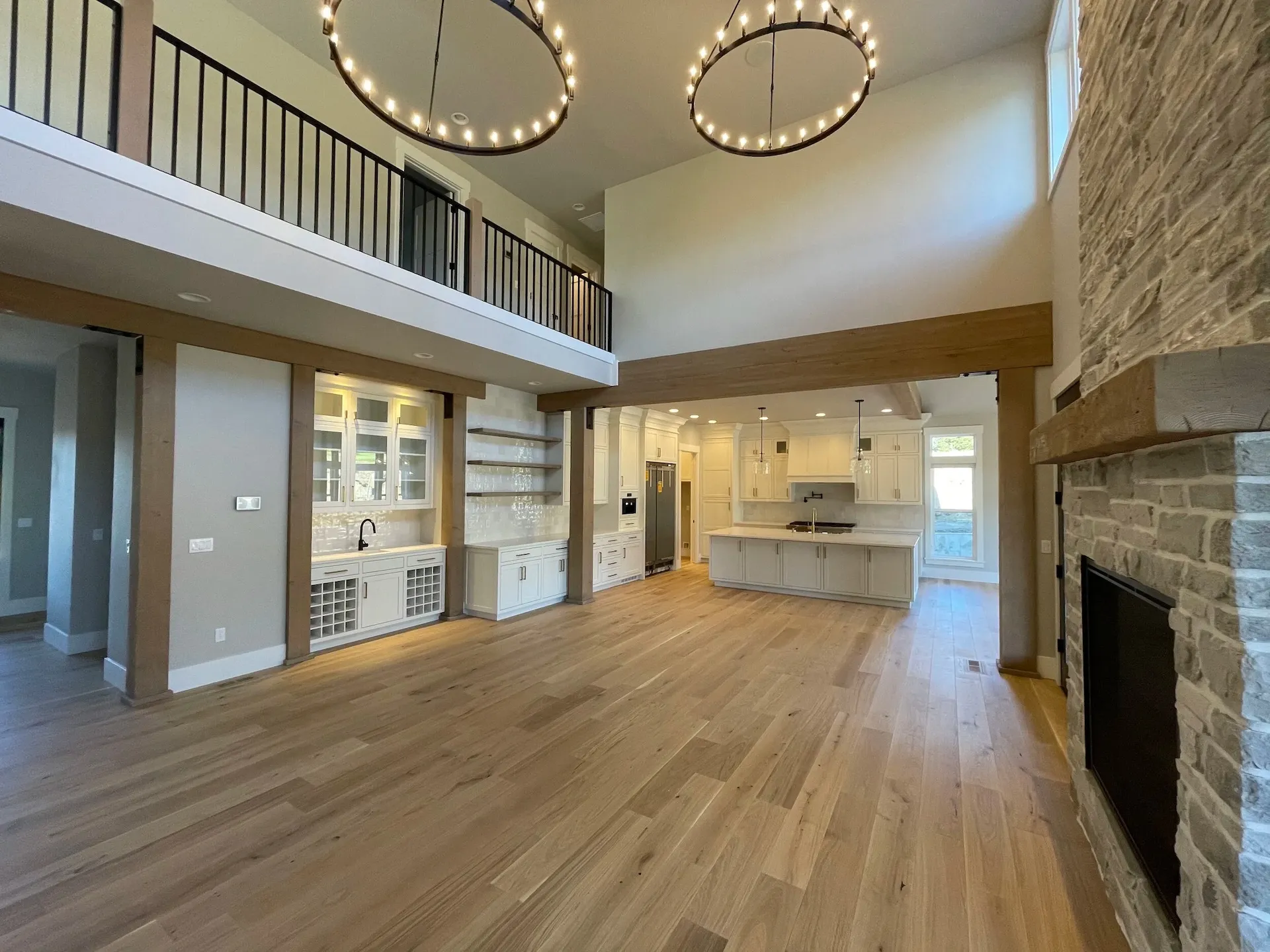 Open-concept living room and kitchen with vaulted ceilings, wood beams, and stone fireplace