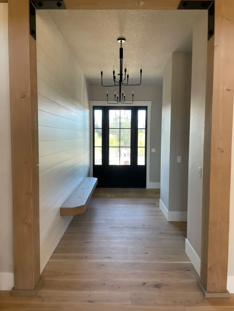 Modern farmhouse entryway with wood beams, black double doors, and floating bench