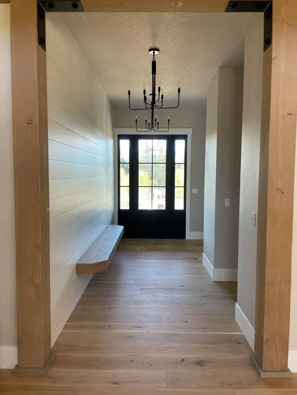 Modern farmhouse entryway with wood beams, black double doors, and floating bench