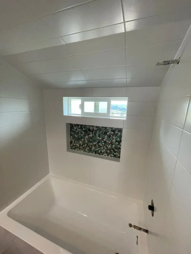 Modern white tiled bathtub surround with mosaic niche accent and clerestory window