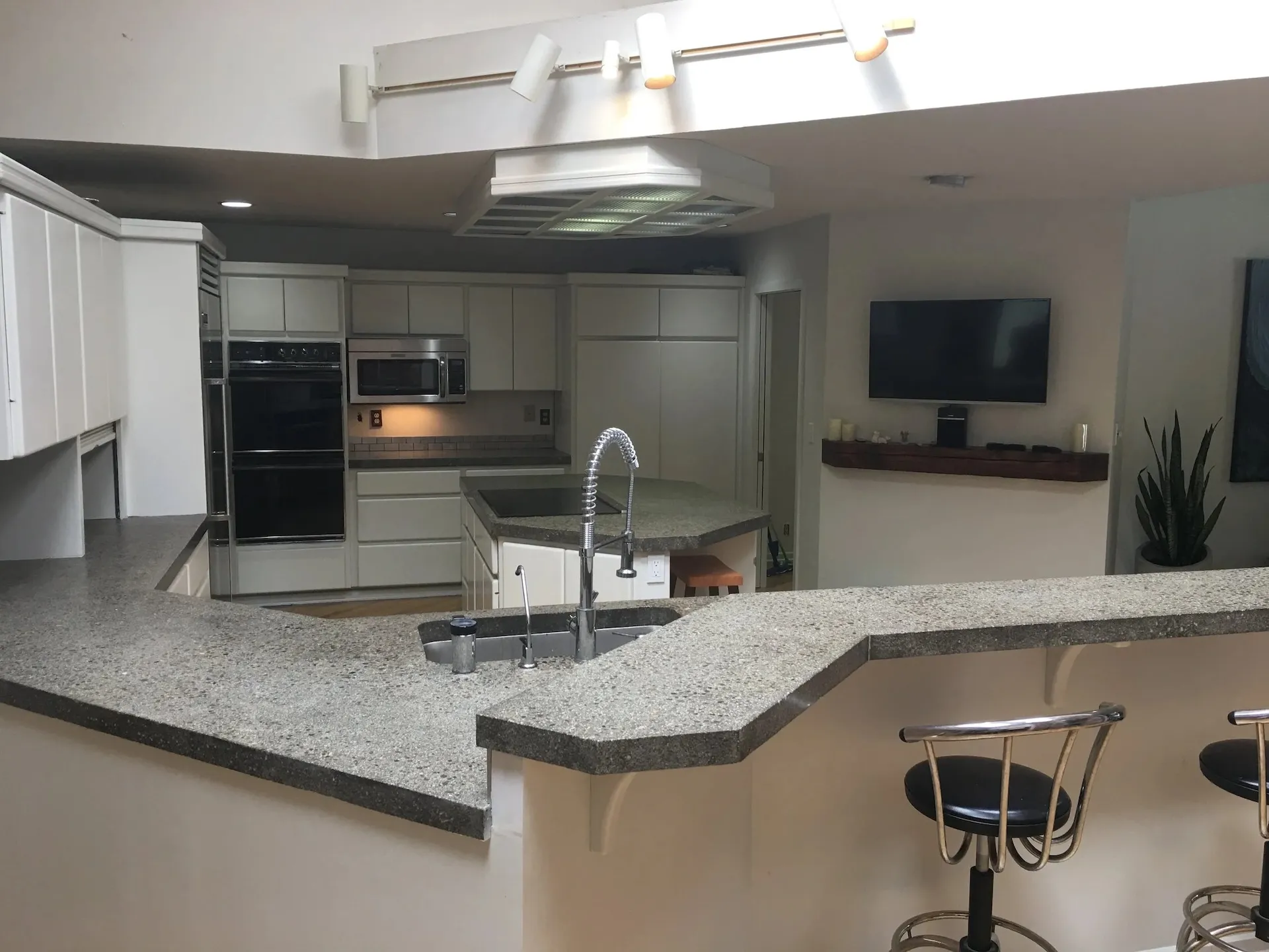 Contemporary kitchen remodel featuring wraparound granite countertops, island sink, and modern white cabinetry