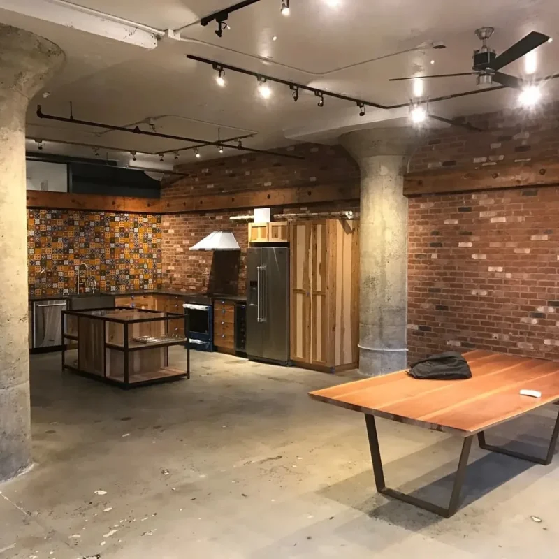 Industrial loft kitchen featuring exposed brick walls, patterned backsplash, and concrete columns interior