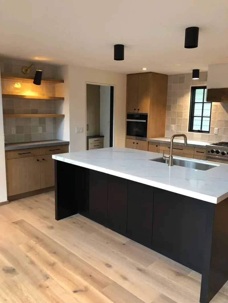 Contemporary kitchen with black island, wood cabinetry, quartz countertops, and floating shelving
