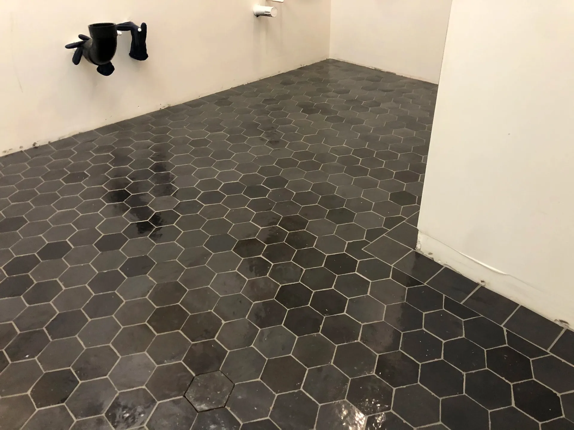 Black hexagon tile flooring with dark grout in modern minimalist bathroom renovation space