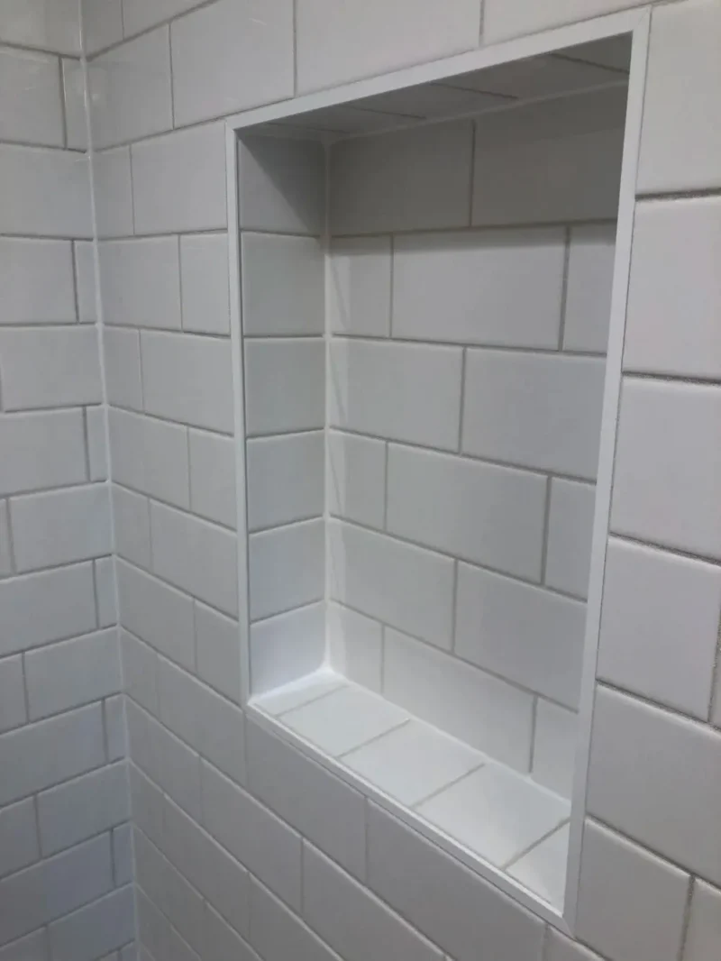 White subway tile shower niche with clean grout lines and recessed storage shelf
