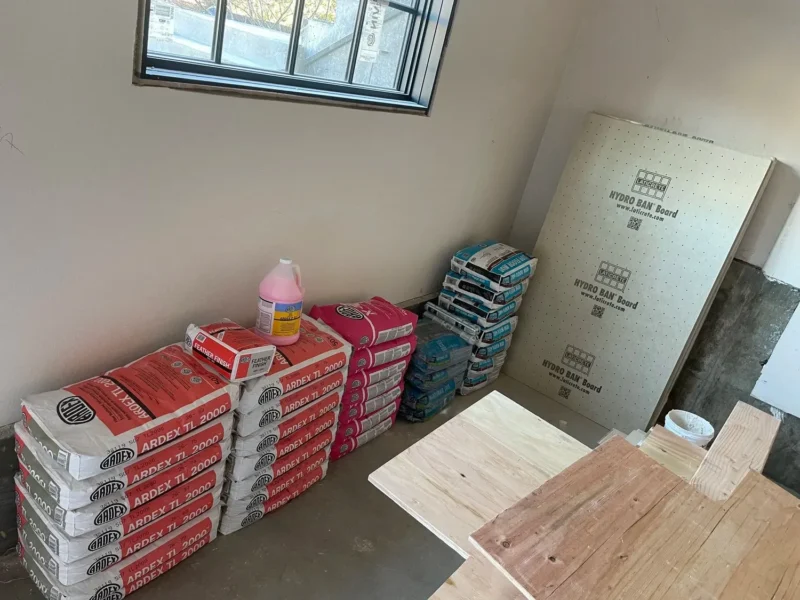 image-asset-64 Tile installation materials including Ardex mortar, Hydro Ban boards, and large format porcelain tiles stacked indoors