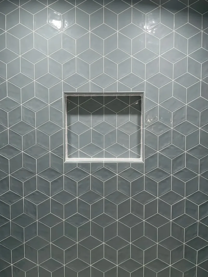 Modern shower wall featuring glossy gray geometric tile pattern with recessed niche for bathroom storage and decor